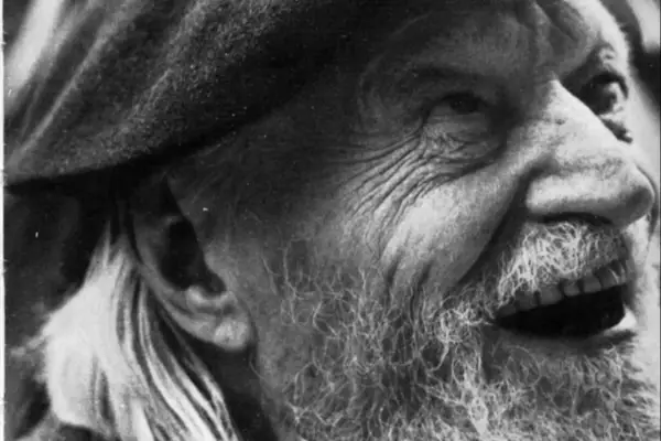 Primo piano di un uomo anziano con barba e cappello, il volto segnato dal tempo, come in un "giorno per giorno Ungaretti".