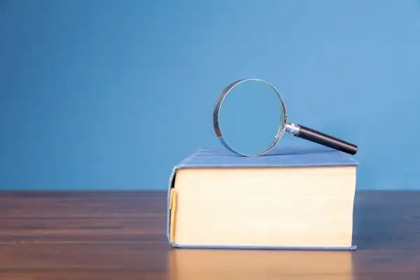 Lente d'ingrandimento su un libro blu, per capire il hic et nunc significato.